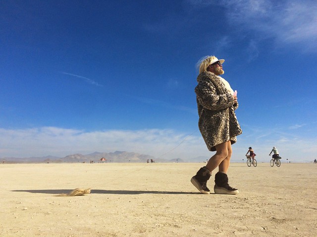 A festivalgoer at Burning Man paces across the desert. Photo by Kevin Cheng