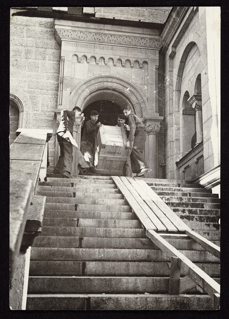 Photograph shows four men carrying a crate of recovered artworks, previously looted by the Nazis during World War II, down a staircase at Neuschwanstein Castle.
