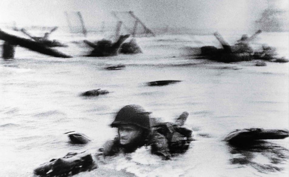 LCIL-88 carried an elite band of Navy demolitionists to Normandy to clear the obstacles that Germans had planted to repel an attack on Omaha Beach, some of which could be seen in Robert Capa's famous photograph of a soldier wading ashore. Library of Congress.
