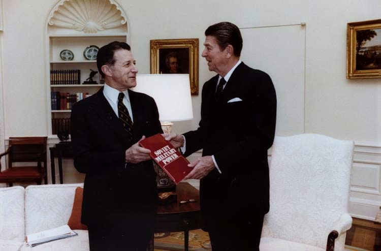 U.S. Secretary of Defense Caspar Weinberger presents President Ronald Reagan with the debut edition of Soviet Military Power, a flagship Defense Intelligence Agency (DIA) publication. Photo Courtesy of Wikimedia Commons.
