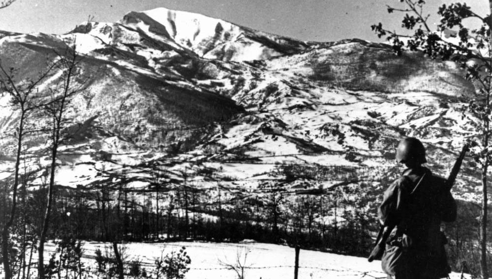 An American soldier contemplates the forbidding Riva Ridge.