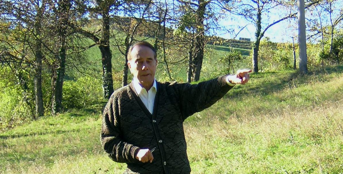 In a visit to the site where he was wounded, Sen. Dole points to where he and his men came down from Monte della Spe. They crossed the ravine and began to climb the hill behind him to his right. Photo by Gabriele Ronchetti. 