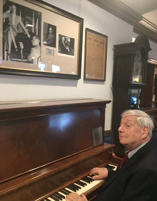 Economist John Tepper Marlin was recently photographed at the famous piano in the National Press Club, like hundreds of others since Bacall sat on it 75 years ago. Photo by Larry Feinberg.