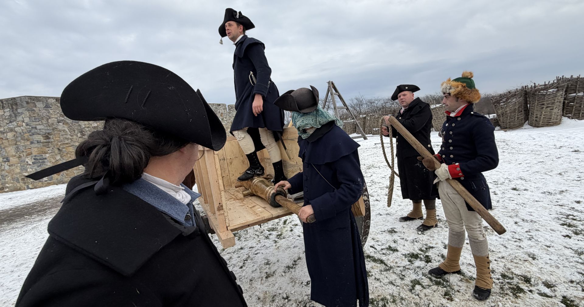Reenactors load a brass cannon into an ox cart